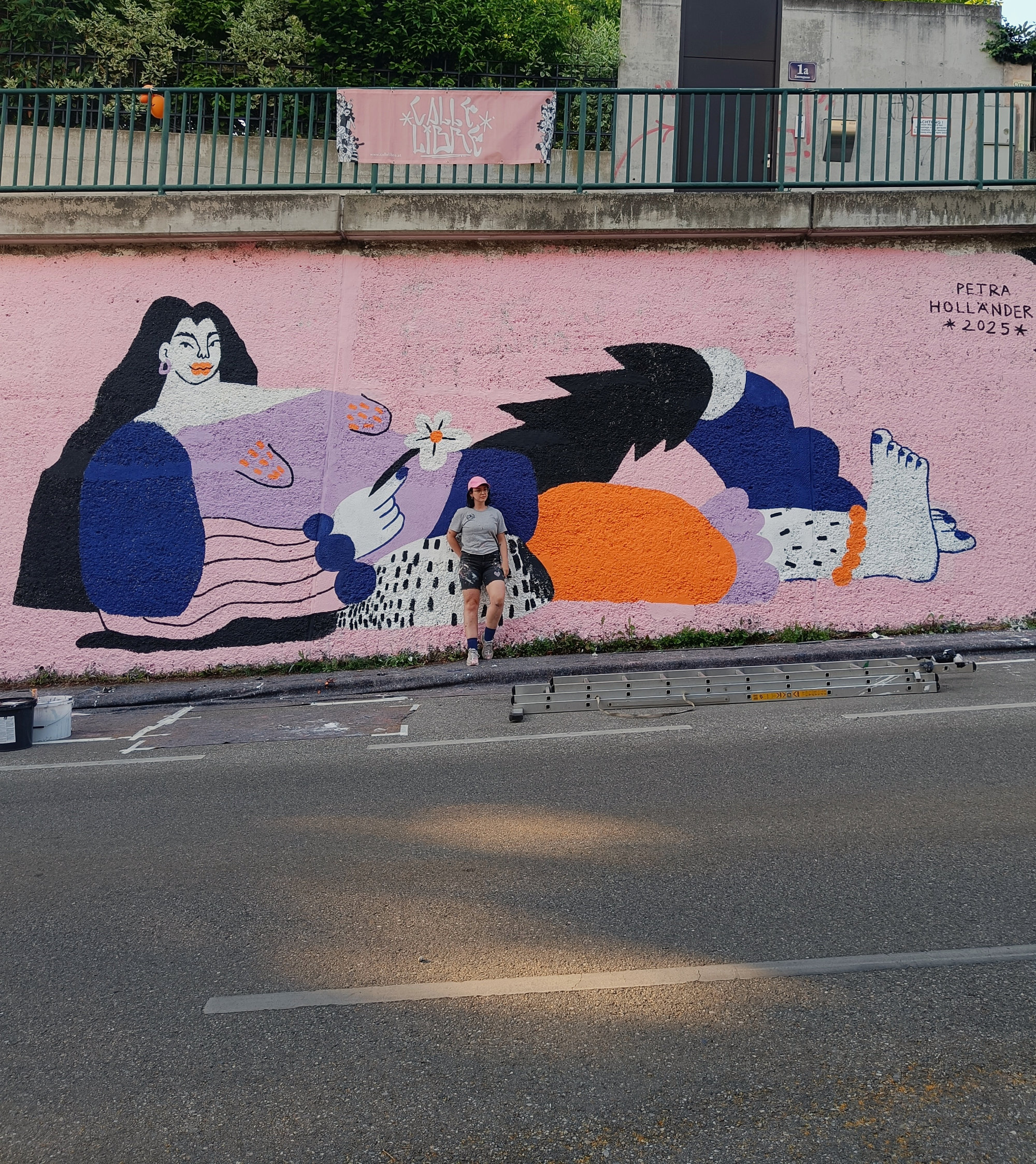 Mural depicting a large woman standing confidently and holding a flower, painted in vivid colors on an outdoor wall. The artwork symbolizes empowerment, self-assurance, and the right to occupy space. Created by four FLINTA artists reclaiming visibility in street art.