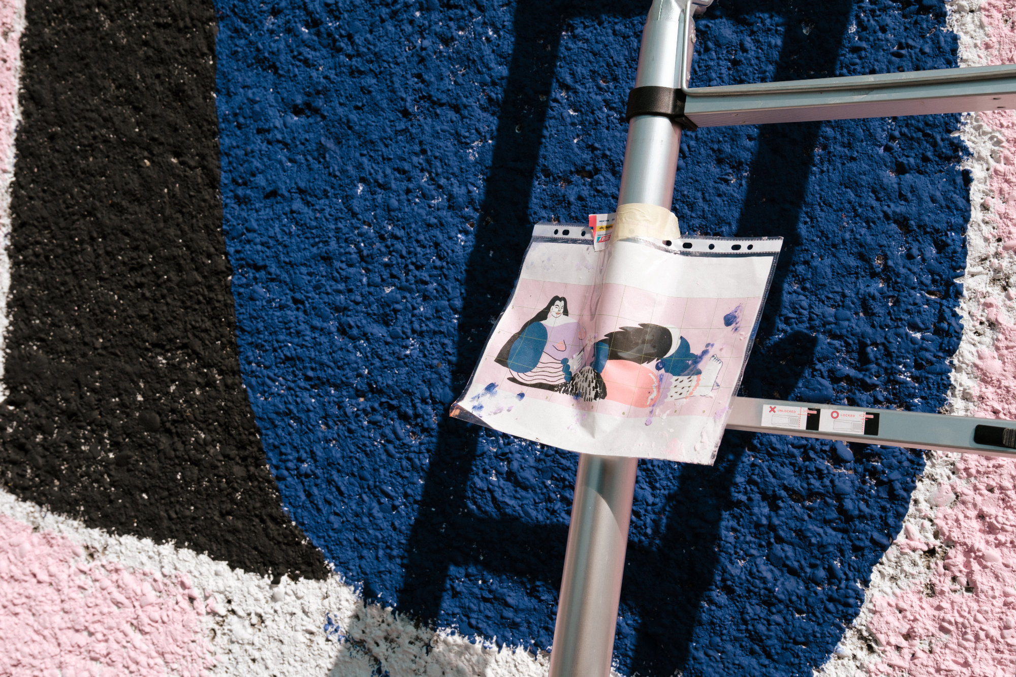 Mural depicting a large woman standing confidently and holding a flower, painted in vivid colors on an outdoor wall. The artwork symbolizes empowerment, self-assurance, and the right to occupy space. Created by four FLINTA artists reclaiming visibility in street art.